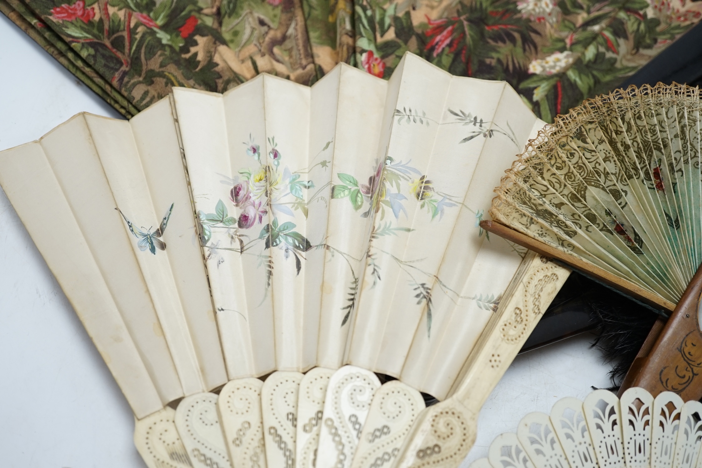 A black ostrich feather and tortoiseshell fan and four others including a carved bone and floral painted silk example. Condition - poor to fair